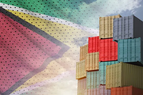 stock image Guyana flag and big stack of shipping cargo containers in docks with sky background close up