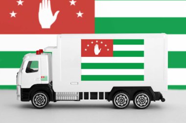 Abkhazia flag depicted on side wall of white delivery van close up. Shipping and local delivery concept clipart