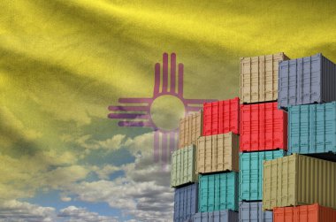 New Mexico US state flag and big stack of shipping cargo containers in docks with sky background close up clipart