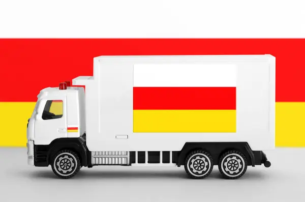 Stock image South Ossetia flag depicted on side wall of white delivery van close up. Shipping and local delivery concept