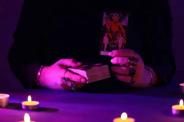 stock image KYIV, UKRAINE - JULY 10, 2024 Tarot reader picking tarot cards. Candlelight in dark room. Tarot reader or fortune teller reading and forecasting close up