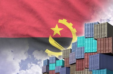 Angola flag and big stack of shipping cargo containers in docks with sky background close up clipart