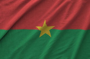 Burkina Faso flag depicted on folded wavy fabric of old cloth close up clipart