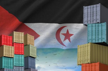 Western Sahara flag and big stack of shipping cargo containers in docks with sky background close up clipart