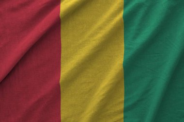 Guinea flag depicted on folded wavy fabric of old cloth close up clipart