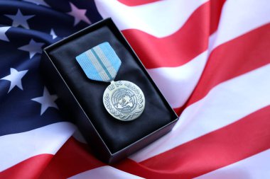 KYIV, UKRAINE - 10 Temmuz 2024 Birleşmiş Milletler uluslararası madalyası. Birleşik Devletler askeri madalyası, kurdele ve broşla. El yapımı kağıt tiyatro dekorları yakın plan.