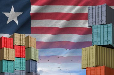 Liberia flag and big stack of shipping cargo containers in docks with sky background close up clipart