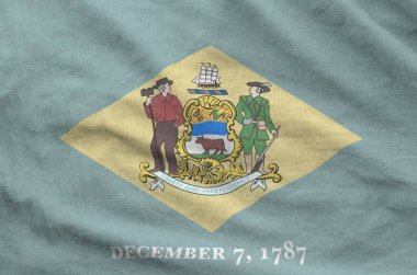 Delaware US state flag depicted on folded wavy fabric of old cloth close up clipart