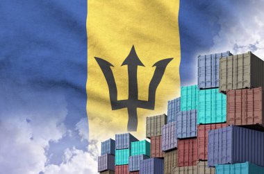 Barbados flag and big stack of shipping cargo containers in docks with sky background close up clipart