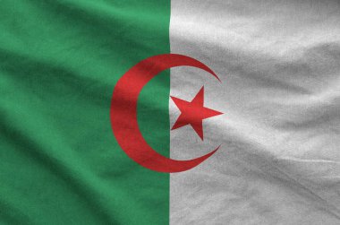 Algeria flag depicted on folded wavy fabric of old cloth close up clipart