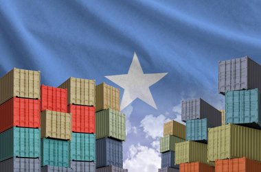 Somalia flag and big stack of shipping cargo containers in docks with sky background close up clipart