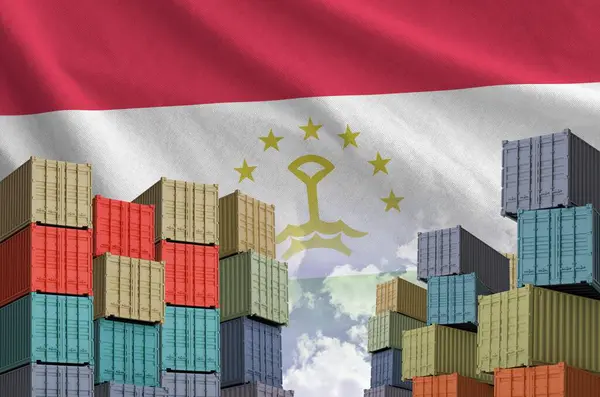 stock image Tajikistan flag and big stack of shipping cargo containers in docks with sky background close up