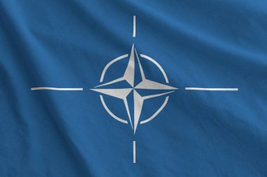Eski kumaşın katlanmış dalgalı kumaşında NATO bayrağı tasvir edilmiştir.