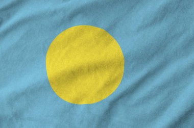 Palau flag depicted on folded wavy fabric of old cloth close up clipart