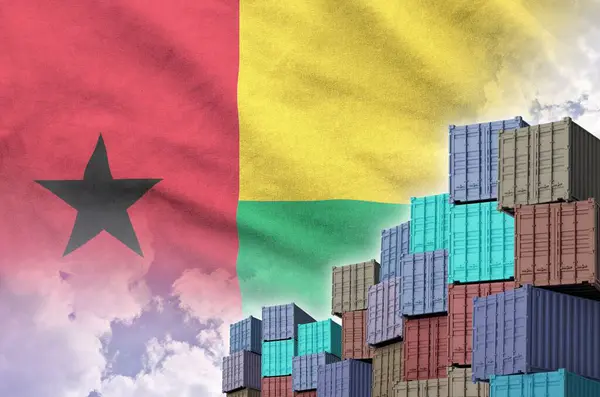 Stock image Guinea Bissau flag and big stack of shipping cargo containers in docks with sky background close up