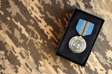 KYIV, UKRAINE - 10 Temmuz 2024 Birleşmiş Milletler uluslararası madalyası. Birleşik Devletler askeri madalyası, kurdele ve broşla. El yapımı kağıt tiyatro dekorları yakın plan.