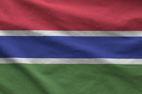 stock image Gambia flag depicted on folded wavy fabric of old cloth close up