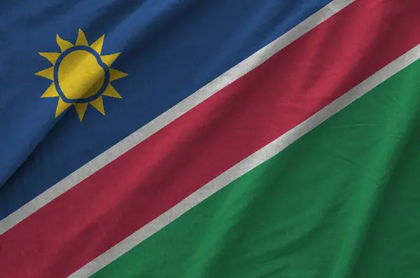 stock image Namibia flag depicted on folded wavy fabric of old cloth close up