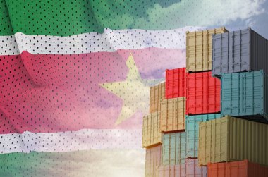 Surinam bayrağı ve yükleme konteynırları rıhtımda gökyüzü arkaplanı kapalı.