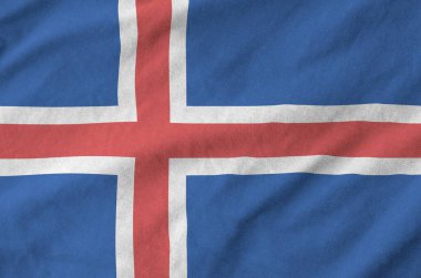 Iceland flag depicted on folded wavy fabric of old cloth close up clipart