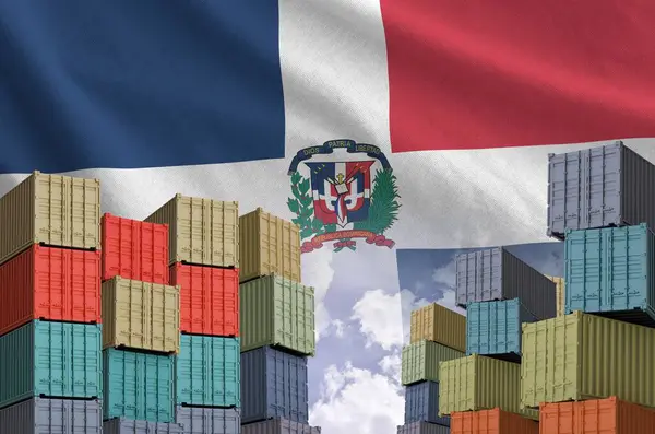 stock image Dominican Republic flag and big stack of shipping cargo containers in docks with sky background close up