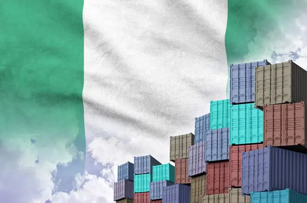 stock image Nigeria flag and big stack of shipping cargo containers in docks with sky background close up