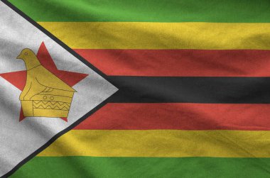 Zimbabwe flag depicted on folded wavy fabric of old cloth close up clipart