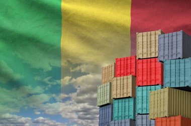 Mali flag and big stack of shipping cargo containers in docks with sky background close up clipart