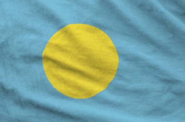 Palau flag depicted on folded wavy fabric of old cloth close up clipart