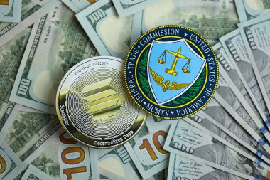 KYIV, UKRAINE - AUGUST 17, 2024 Solana SOL coin and US Federal Trade Commission sign on many USD dollar money bills close up clipart