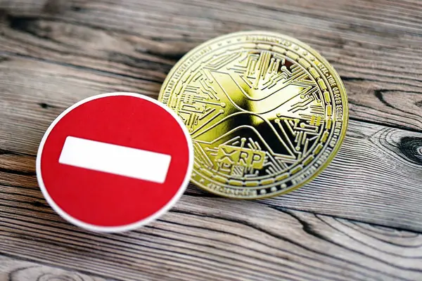 stock image KYIV, UKRAINE - AUGUST 17, 2024 Ripple XRP Coin and red paper stop sign on wooden background close up