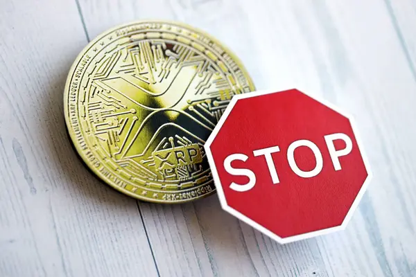 stock image KYIV, UKRAINE - AUGUST 17, 2024 Ripple XRP Coin and red paper stop sign on wooden background close up