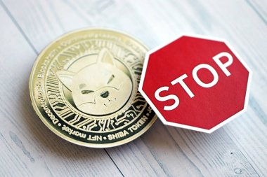 KYIV, UKRAINE - AUGUST 17, 2024 Shiba coin and red paper stop sign on wooden background close up clipart