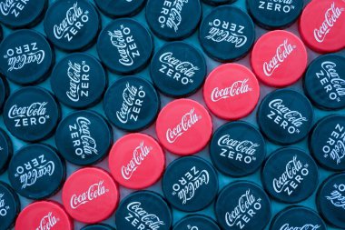 KYIV, UKRAINE - 29 Ocak 2025 Coca Cola Plastik şişe kapağı arka plan. Kapak malzemesi geri dönüştürülebilir. Plastik şişelerin kapaklarını geri dönüşümden önce çıkar.