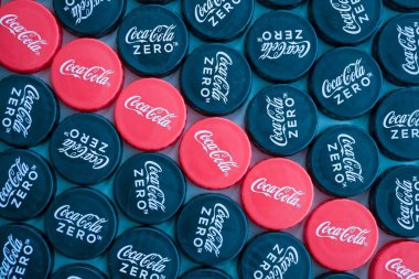 KYIV, UKRAINE - 29 Ocak 2025 Coca Cola Plastik şişe kapağı arka plan. Kapak malzemesi geri dönüştürülebilir. Plastik şişelerin kapaklarını geri dönüşümden önce çıkar.