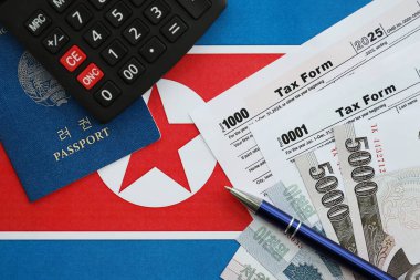 Kuzey Kore büyük miktarlarda para kazandı. Masada kalem, hesap makinesi, pasaport ve vergi formları var. Vergi ödeme ve muhasebe kavramı