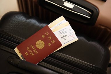 Biletli Japon pasaportu havaalanı bekleme salonundaki turistik bavulun üzerinde yatıyor. Dünya çapında seyahat ve uluslararası turizm kavramı