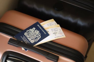 Biletli İngiliz pasaportu havaalanı bekleme salonundaki turistik bavulun üzerinde yatıyor. Dünya çapında seyahat ve uluslararası turizm kavramı