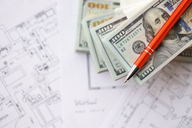 Kalemle birlikte yüklü miktarda Amerikan doları banknotları ve konut projesinin planları yakın plan. Yatırım ve inşaat projesi kavramı
