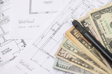 Kalemle birlikte yüklü miktarda Amerikan doları banknotları ve konut projesinin planları yakın plan. Yatırım ve inşaat projesi kavramı