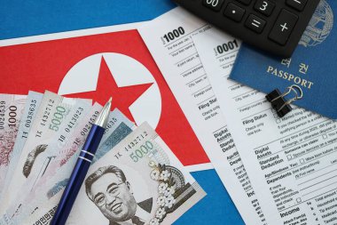 Kuzey Kore büyük miktarlarda para kazandı. Masada kalem, hesap makinesi, pasaport ve vergi formları var. Vergi ödeme ve muhasebe kavramı