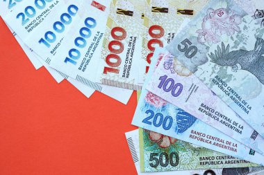Arjantin pezosu büyük miktarlarda para kırmızı renkli masaya yakın duruyor. Finans ve bankacılık kavramı