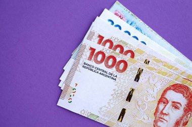 Arjantin pezosu büyük miktarda para mor renkli masaya yakın duruyor. Finans ve bankacılık kavramı