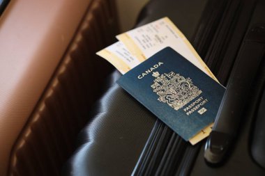 Biletli Kanada pasaportu havaalanı bekleme salonundaki turistik bavulun üzerinde yatıyor. Dünya çapında seyahat ve uluslararası turizm kavramı