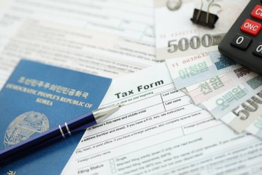 Kuzey Kore büyük miktarlarda para kazandı. Masada kalem, hesap makinesi, pasaport ve vergi formları var. Vergi ödeme ve muhasebe kavramı