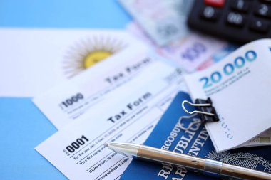 Arjantin Pezosu 'nun para faturaları kalem, hesap makinesi, pasaport ve vergi formlarıyla dolu. Finans ve bankacılık kavramı