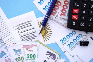 Arjantin Pezosu 'nun para faturaları kalem, hesap makinesi, pasaport ve vergi formlarıyla dolu. Finans ve bankacılık kavramı