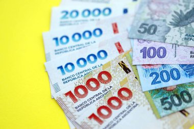 Arjantin pezosu büyük miktarlarda banknotlar sarı renkli masaya yakın duruyor. Finans ve bankacılık kavramı