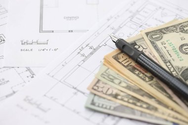 Kalemle birlikte yüklü miktarda Amerikan doları banknotları ve konut projesinin planları yakın plan. Yatırım ve inşaat projesi kavramı