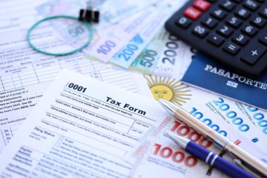 Arjantin Pezosu 'nun para faturaları kalem, hesap makinesi, pasaport ve vergi formlarıyla dolu. Finans ve bankacılık kavramı